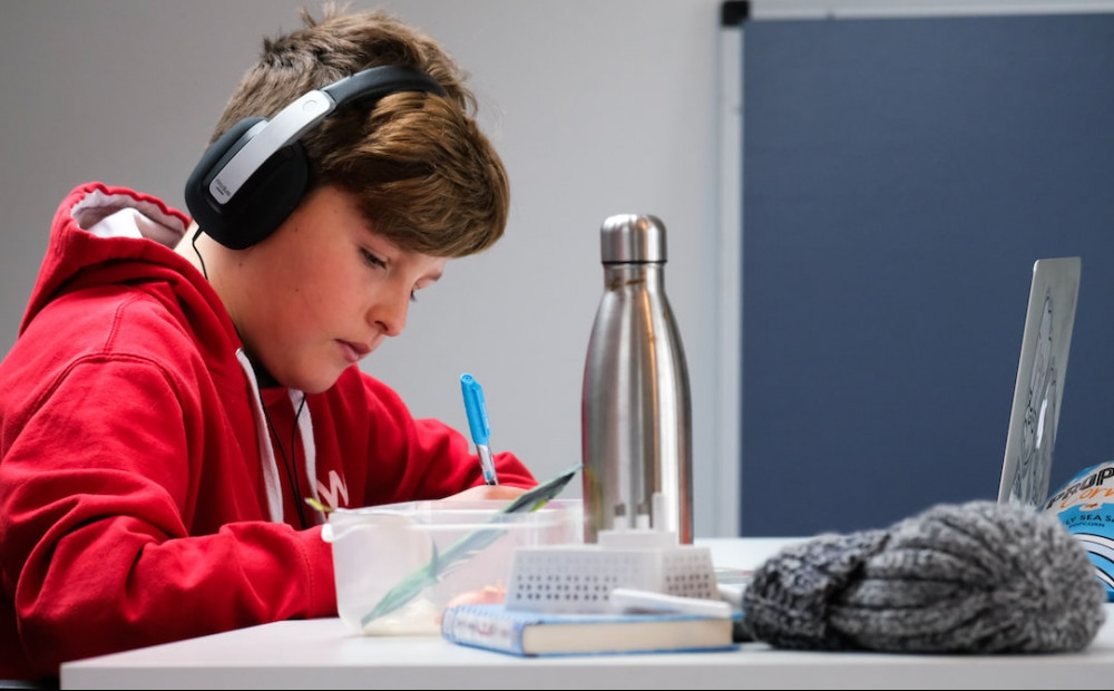 child doing homework with headphones on